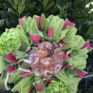 Lime green deco mesh wreath with pink ribbons, green hydrangeas and a praying angel child picture at the centre – hand-made artificial wreath by Shamitay